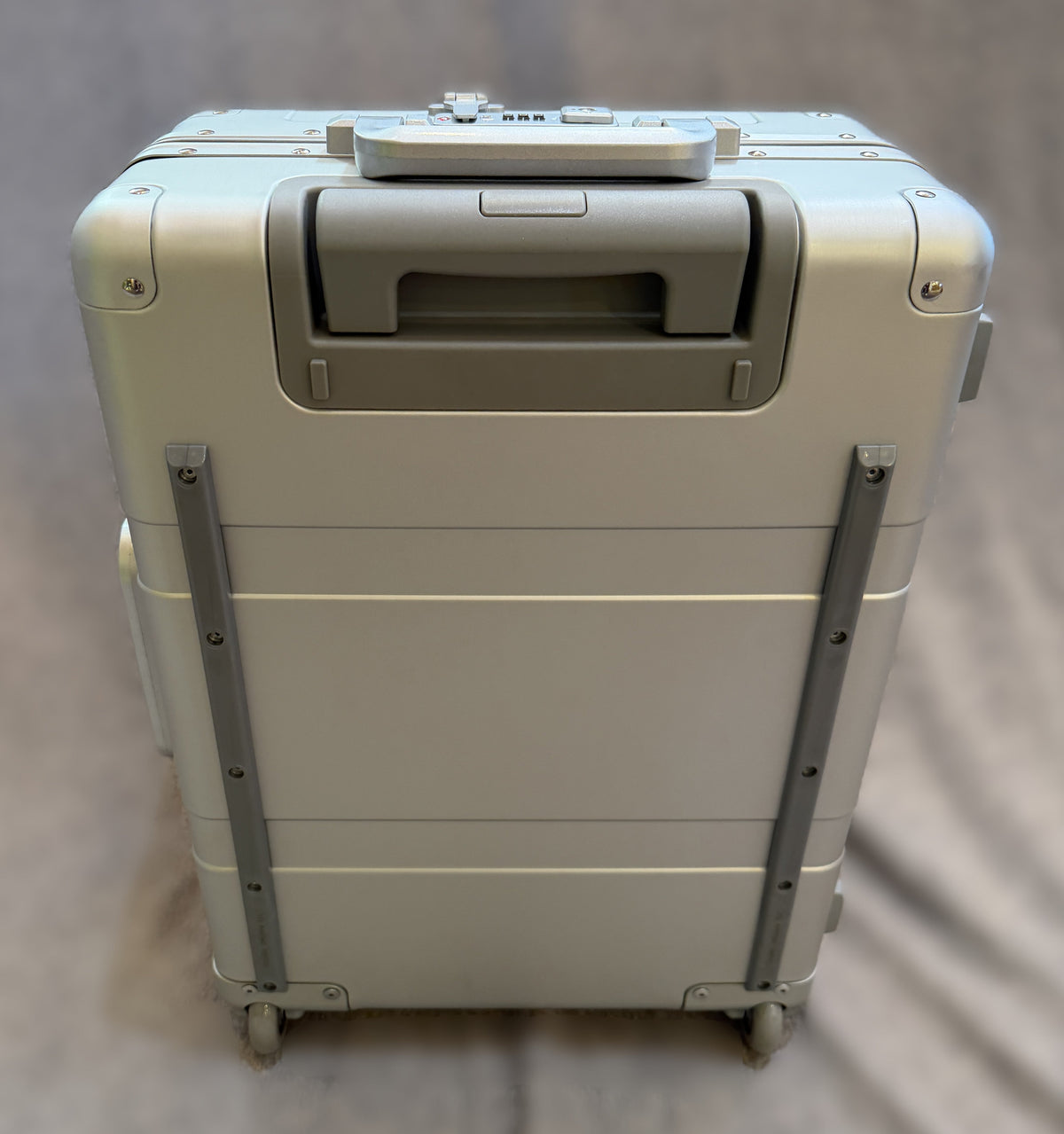 Rear view of the Paradox Aviation GEN2 22-inch silver aluminum roll aboard suitcase with matte grey handle and wheels.