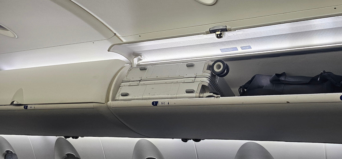 Paradox Aviation 22 inch GEN2 Frequent Flyer silver carry-on luggage stored in a CRJ-200 airplane overhead bin